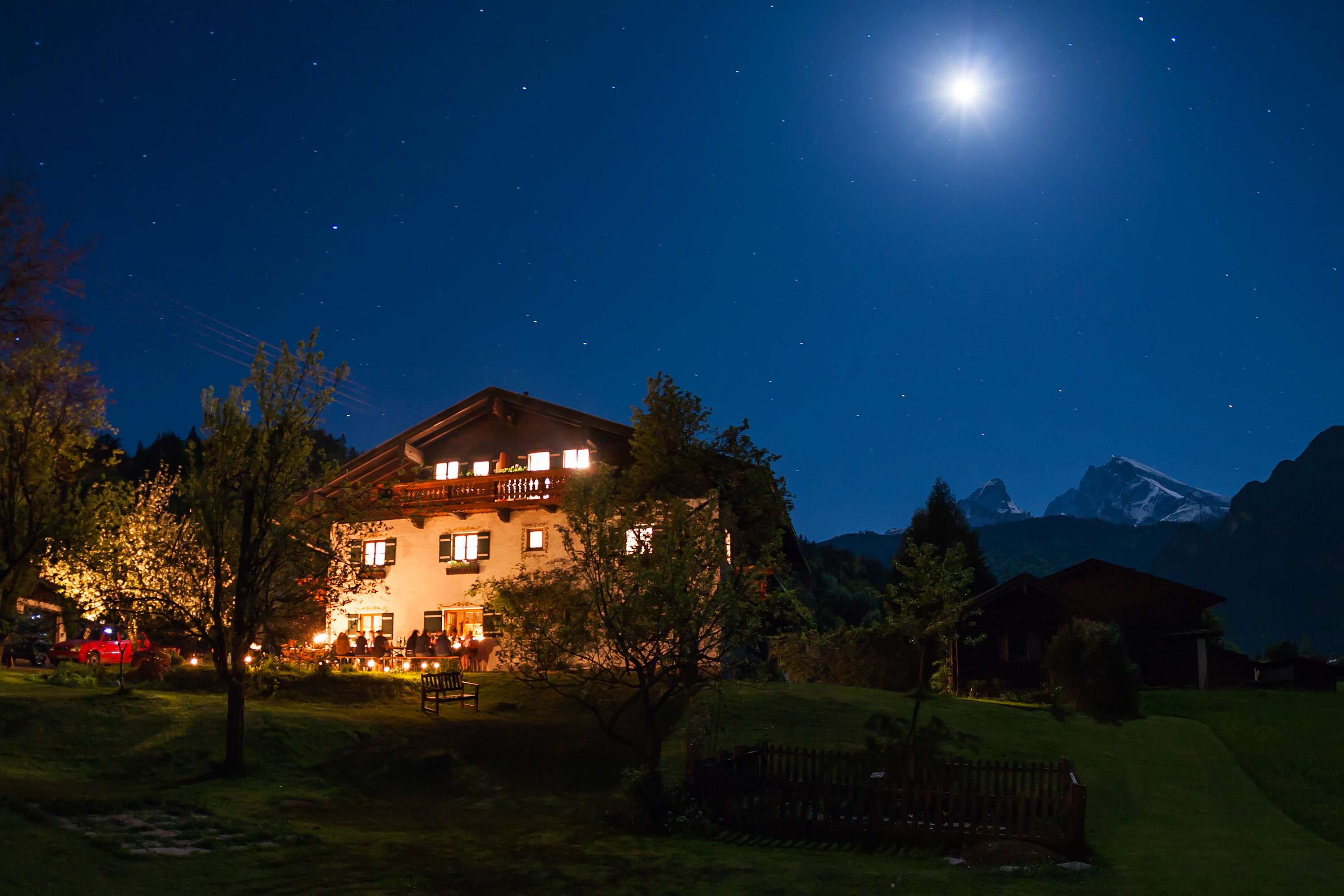 Schralterlehen in Schönau am Königssee bei Nacht mit beleuchteten Fenstern, Sternenhimmel, Vollmond und Watzmann im Hintergrund